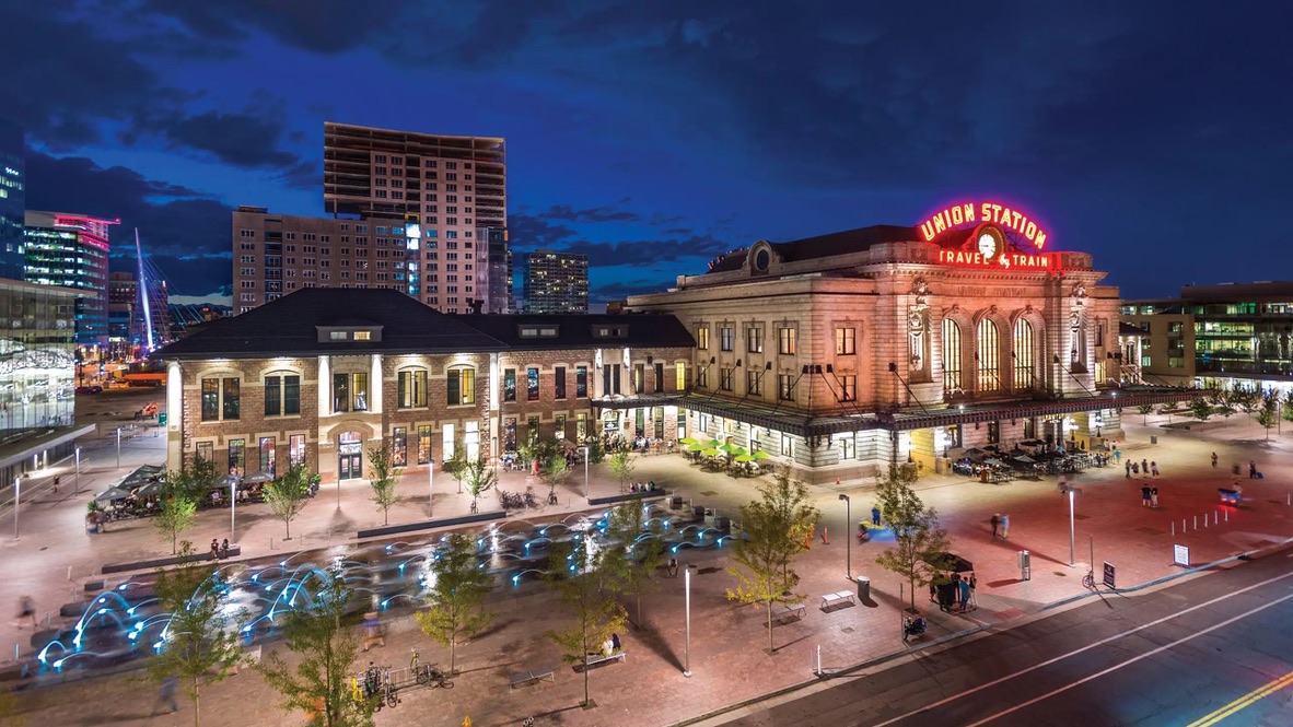 Denver Union Station lit up at night, seen from above across the plaza and its glowing fountain